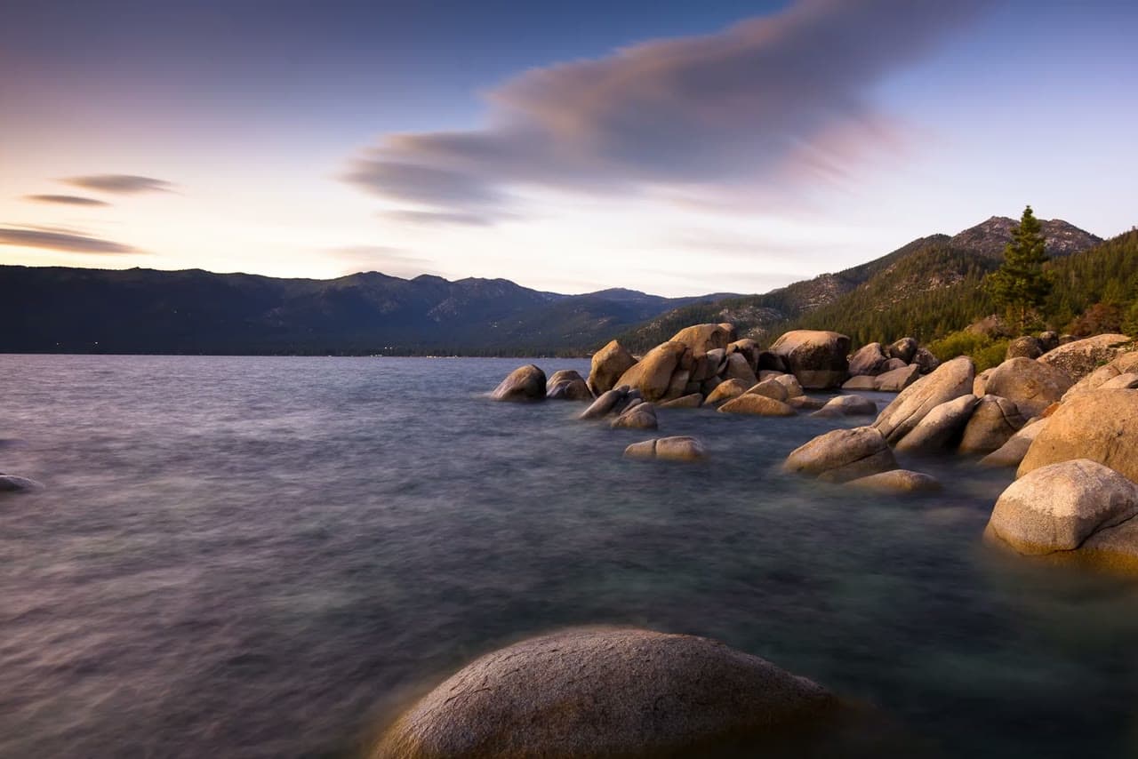 Granite boulders on a mountain lake shore at dusk