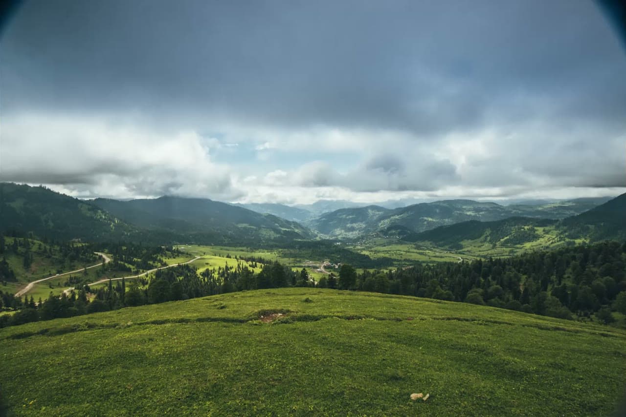 A wide green valley under a storm sky